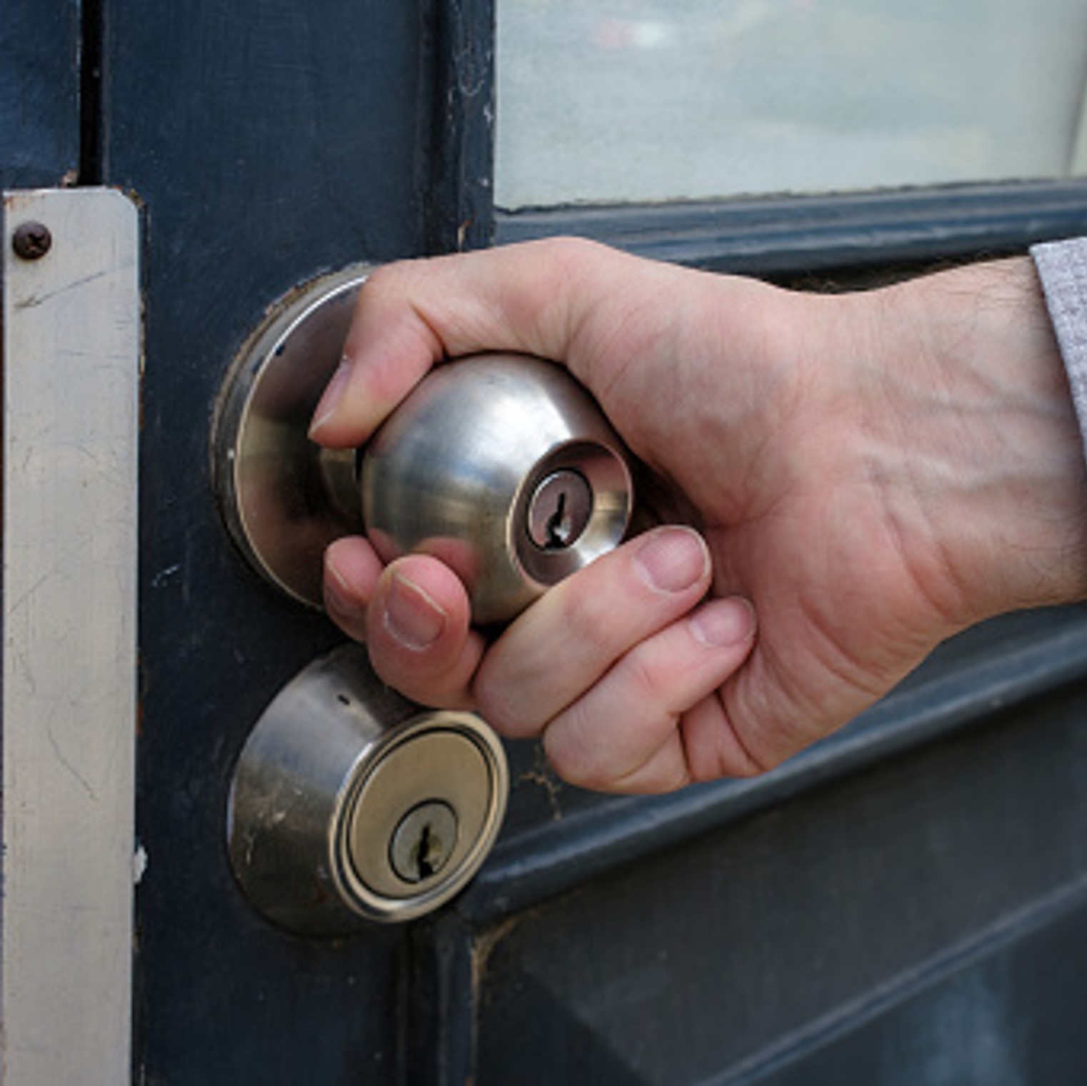 Imatge d'un home comprovant si la porta de casa està ben tancada